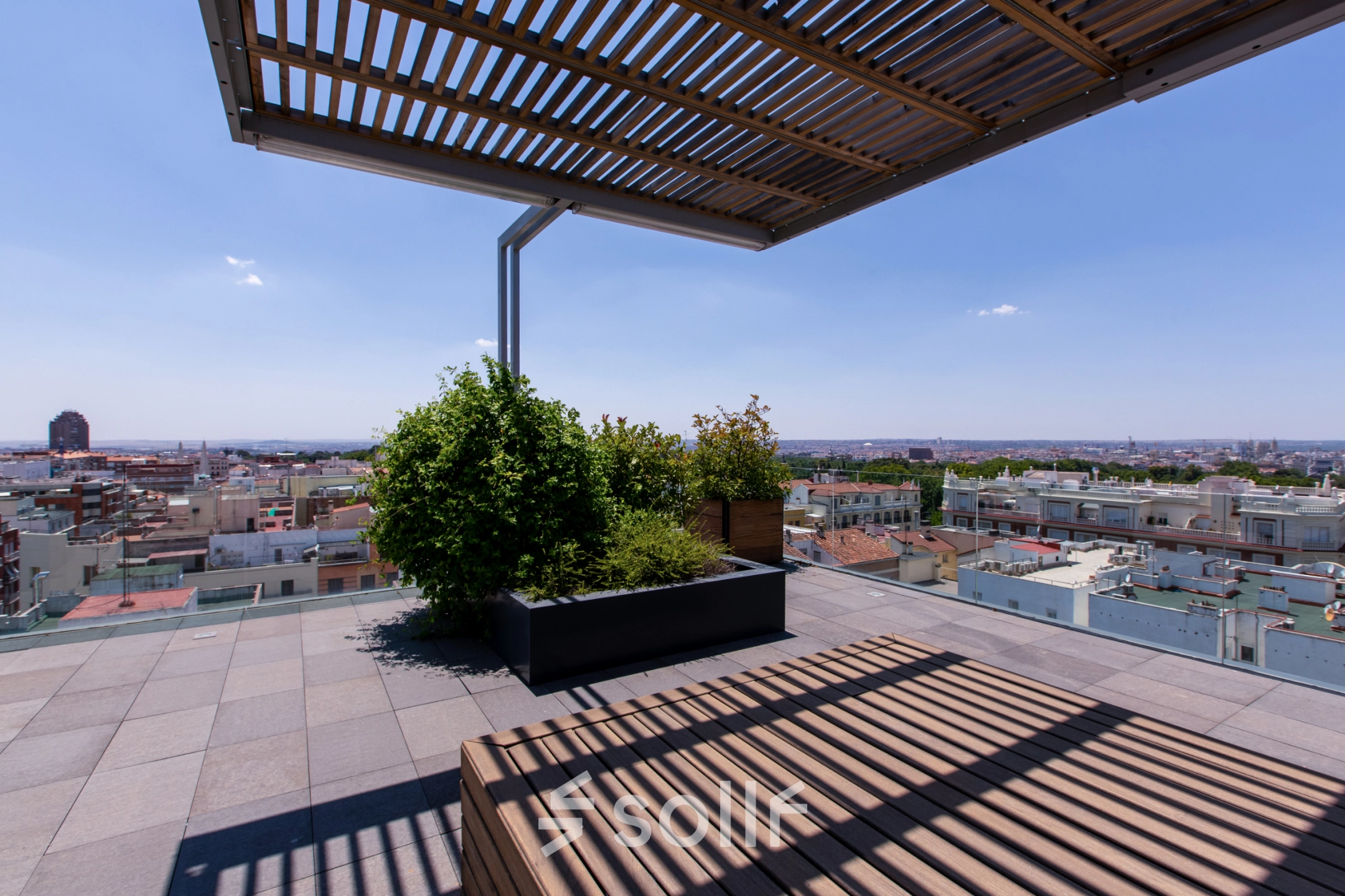 Roof terrace view at an office to rent on calle de O'Donnell, Madrid Retiro, featuring a wooden pergola and cityscape.