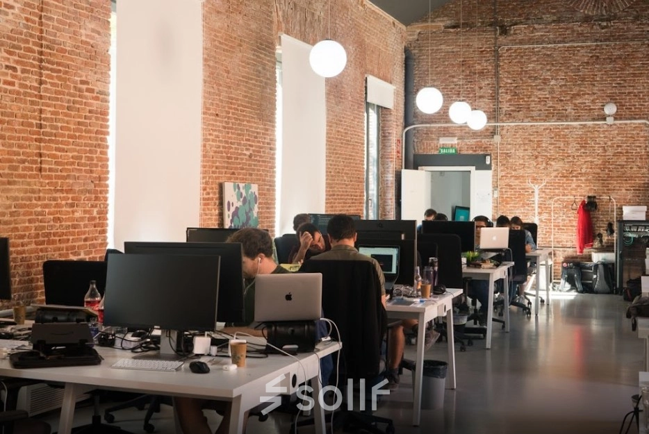 Modern office space for rent on Calle Vandergoten 1, Madrid Retiro, featuring open workstations and professionals engaged in computer work.