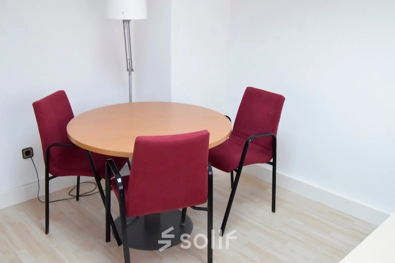 Cozy office space rental at Calle Capitan Haya 60 in Madrid Tetuán, featuring a small round table with red chairs, perfect for meetings.