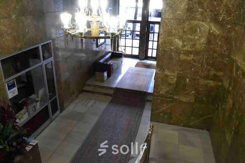 Spacious, marble-walled entrance hall with a chandelier, offering a welcoming ambiance for office space rental inquiries at Calle Capitan Haya 60, Madrid Tetuán.