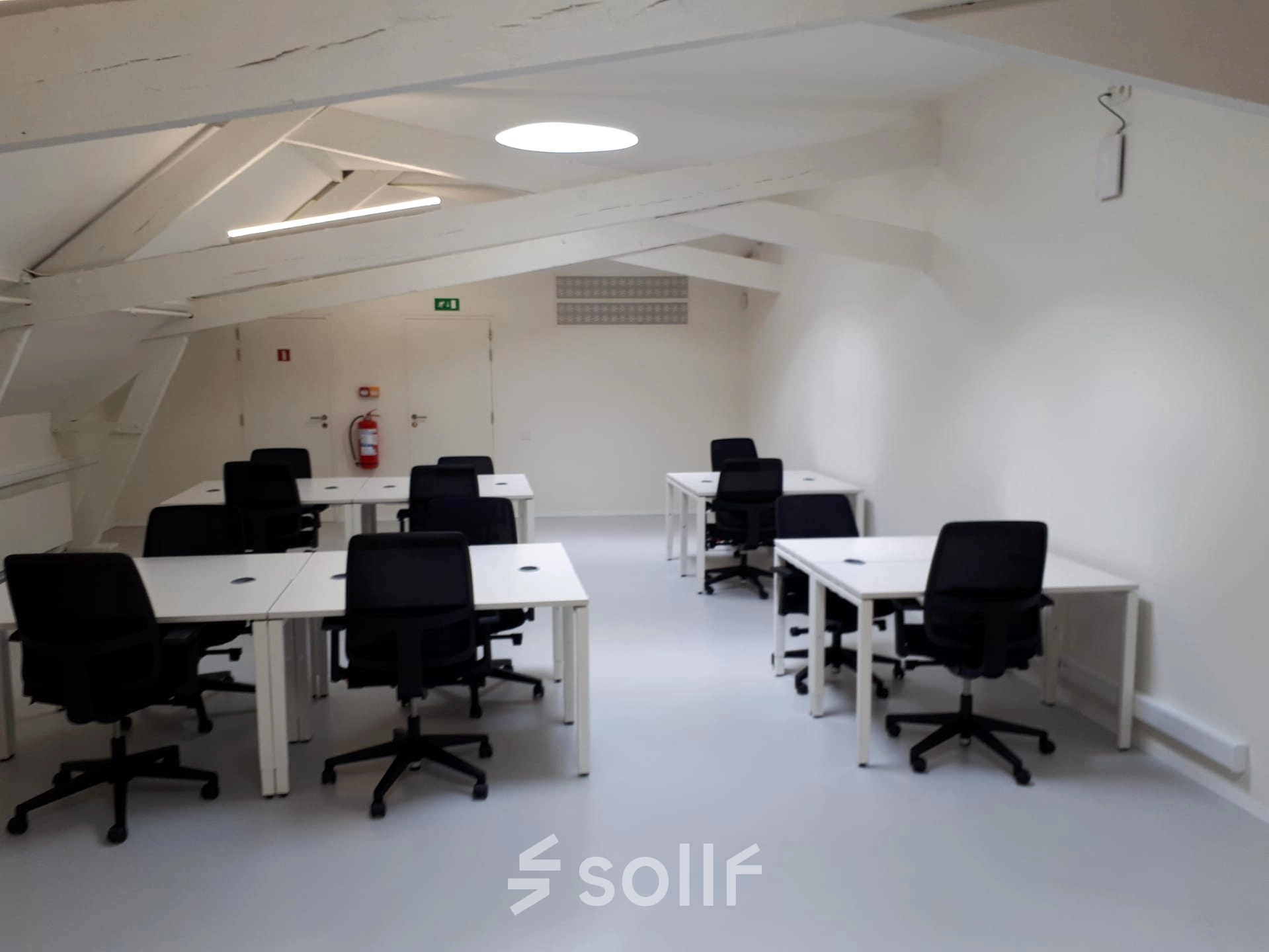 Bright office space available for rent in Mechelen Centrum, featuring black chairs and white desks under modern lighting.