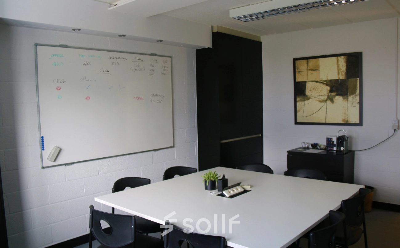 A bright conference room at De Regenboog 11, Mechelen North, featuring a large whiteboard and a modern table. Ideal for an office space rental.