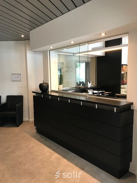 Reception area at De Regenboog 11 in Mechelen North, ideal for office space rental with a sleek desk and modern decor.