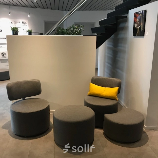 Cozy furnished office space with seating arrangement under a staircase at De Regenboog 11, ideal for those seeking office space rental in Mechelen North.