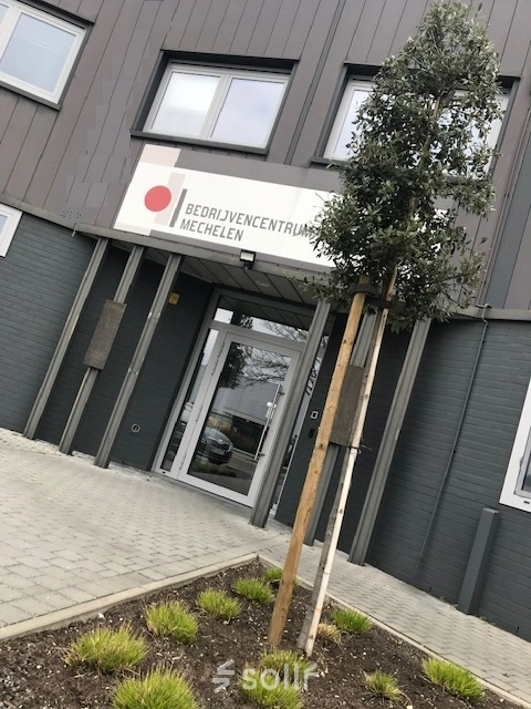 Exterior view of an office building entrance at De Regenboog 11, Mechelen North, suitable for office space rental.