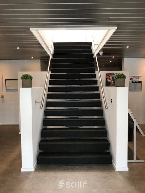 Interior view of an office entrance with a central staircase leading upwards. Suitable for office space rental.