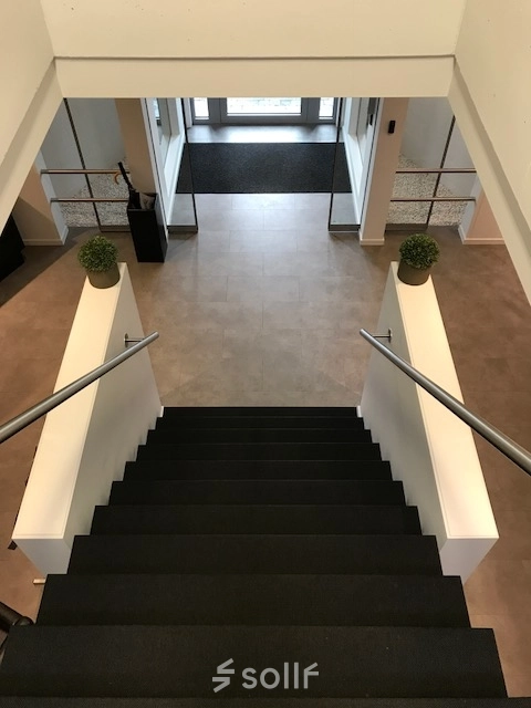 Bright office entrance with modern staircase at De Regenboog 11, ideal for office space rental in Mechelen North.