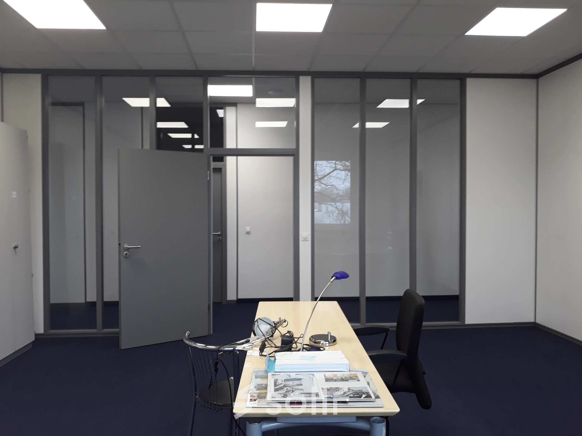 Modern office space at Landsberger Straße 428, München Pasing, featuring a tidy desk setup with chairs against a backdrop of partitioned walls, ideal for office space rental.