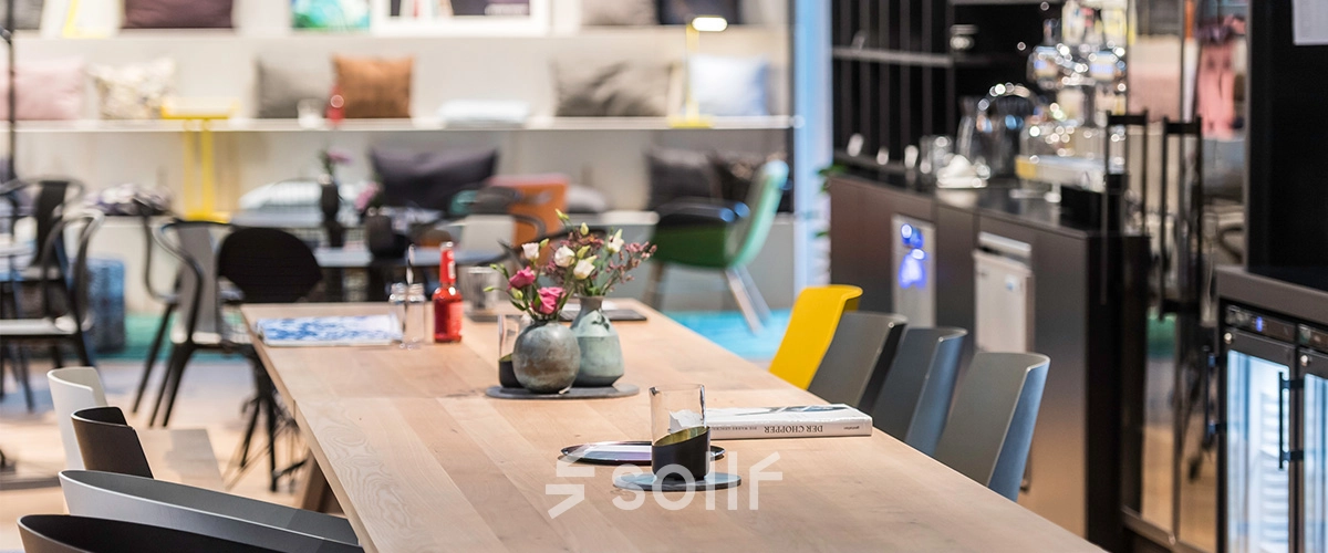 Modern office space available for rent at Rosenheimer Straße 143C, München Werksviertel, featuring a long wooden table with colorful chairs and a cozy, inviting atmosphere.
