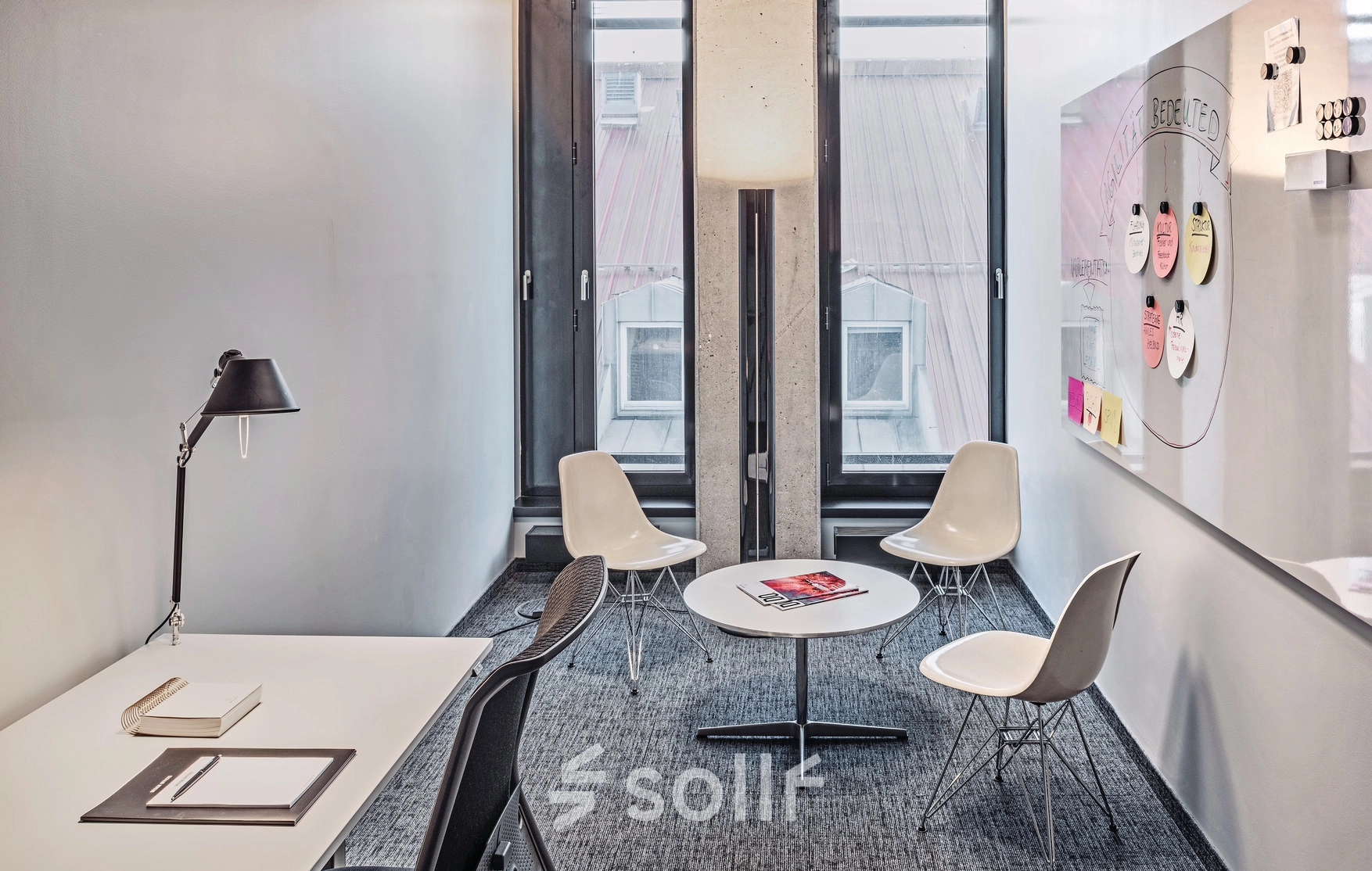 Bright office space for rent at Rosenheimer Straße 143C, München Werksviertel, featuring a meeting area with chairs and a desk with a lamp.