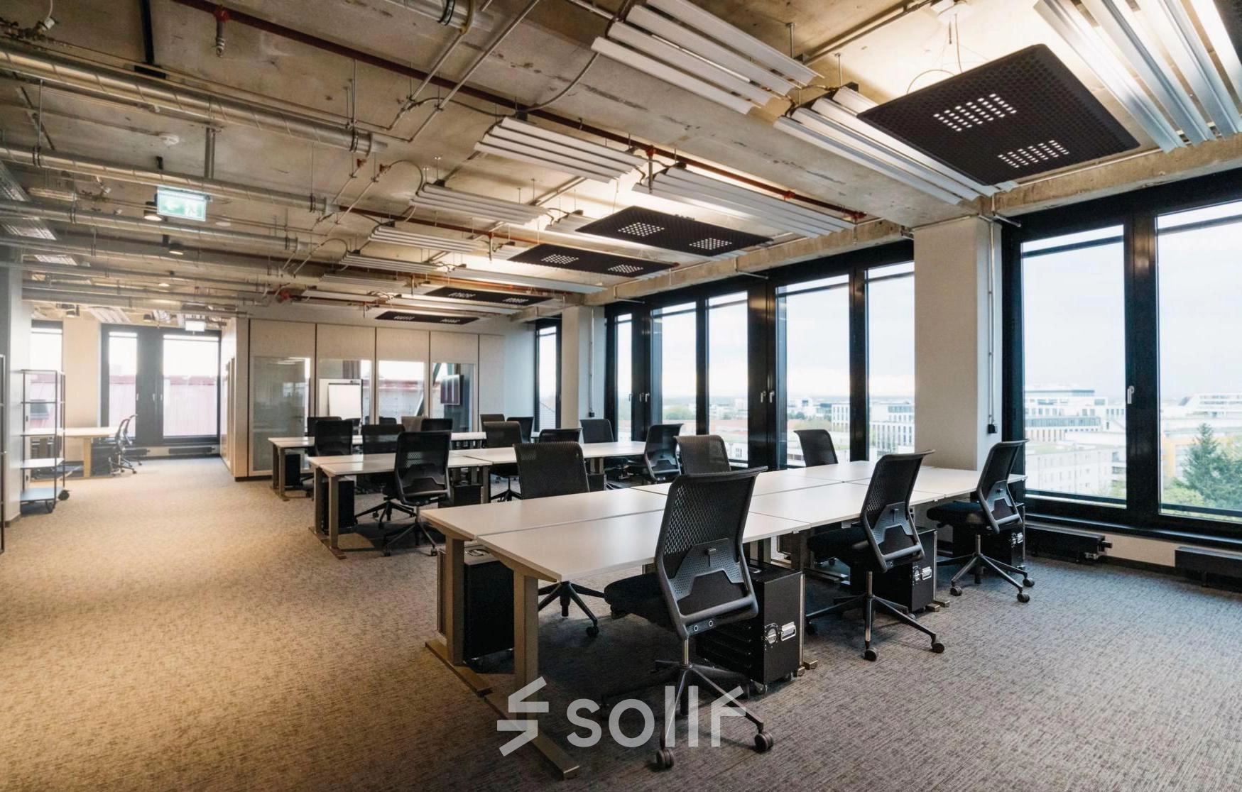 Spacious office space with modern furnishings and large windows at Rosenheimer Straße 143C, München Werksviertel, ideal for professionals seeking office space rental with ample natural light and ergonomic seating.
