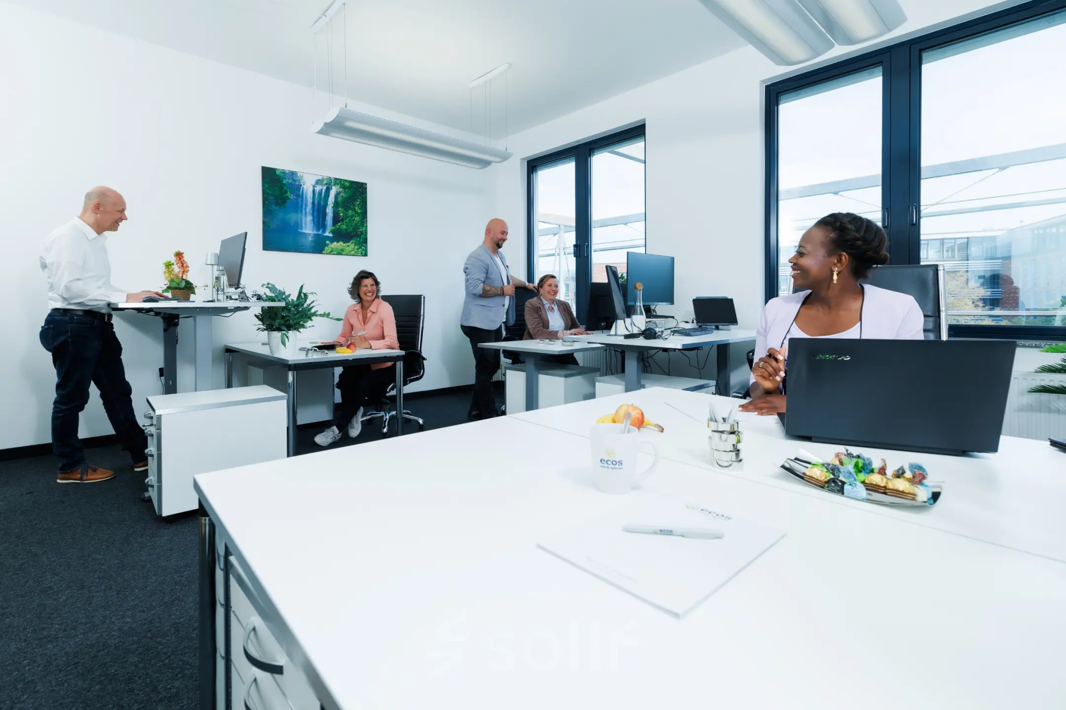 A modern office space at Landsberger Straße 155, Munich Laim, with people collaborating at desks. Ideal for those looking to rent office space in a vibrant setting.