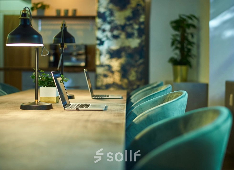 Cozy office space rental at Amalienstraße 71, Munich Maxvorstadt, featuring a long table, chairs, and laptops, perfect for collaborative work.