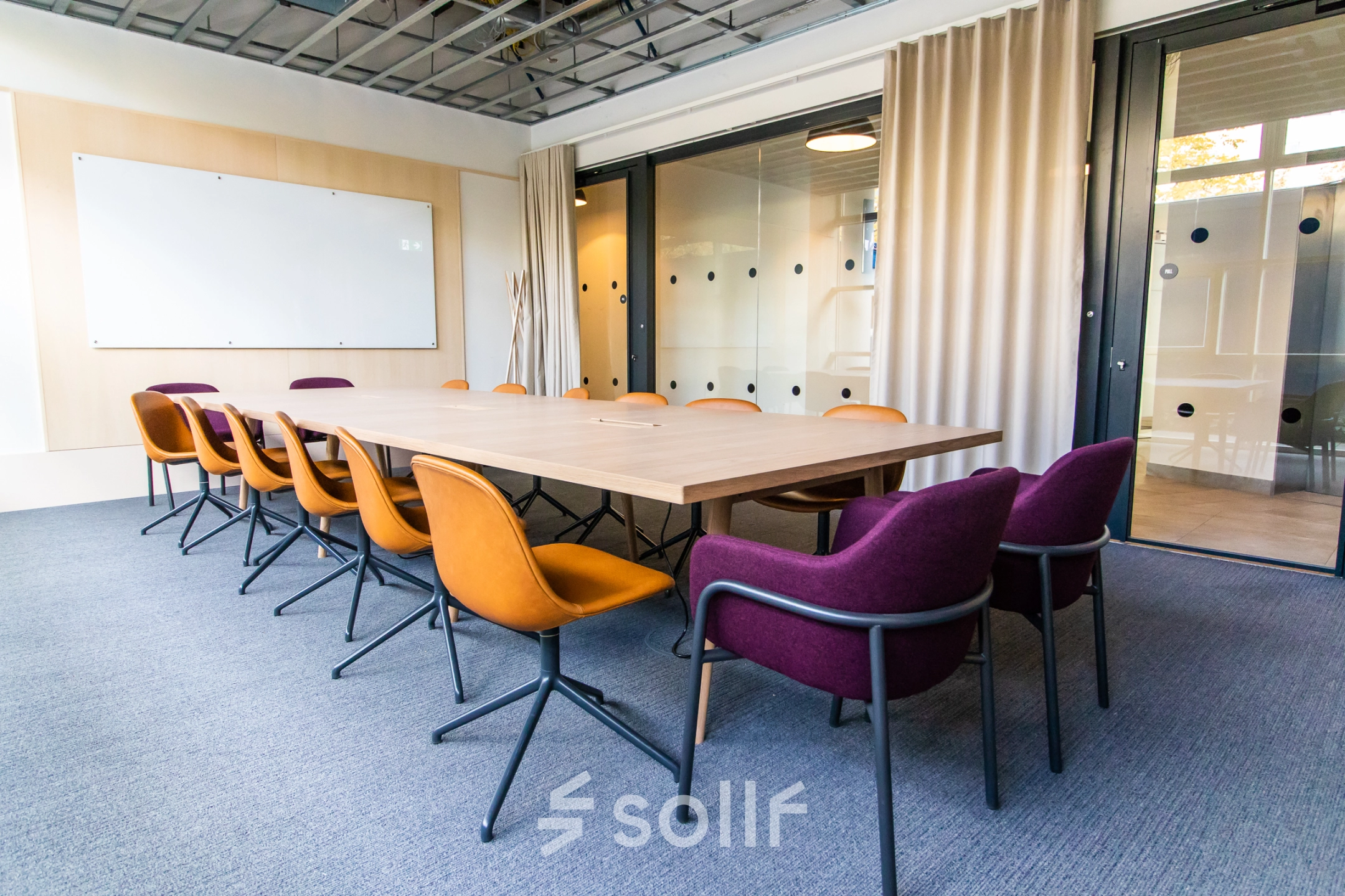Modern conference room with a large wooden table and colorful chairs, ideal for office space rental in Munich Maxvorstadt.
