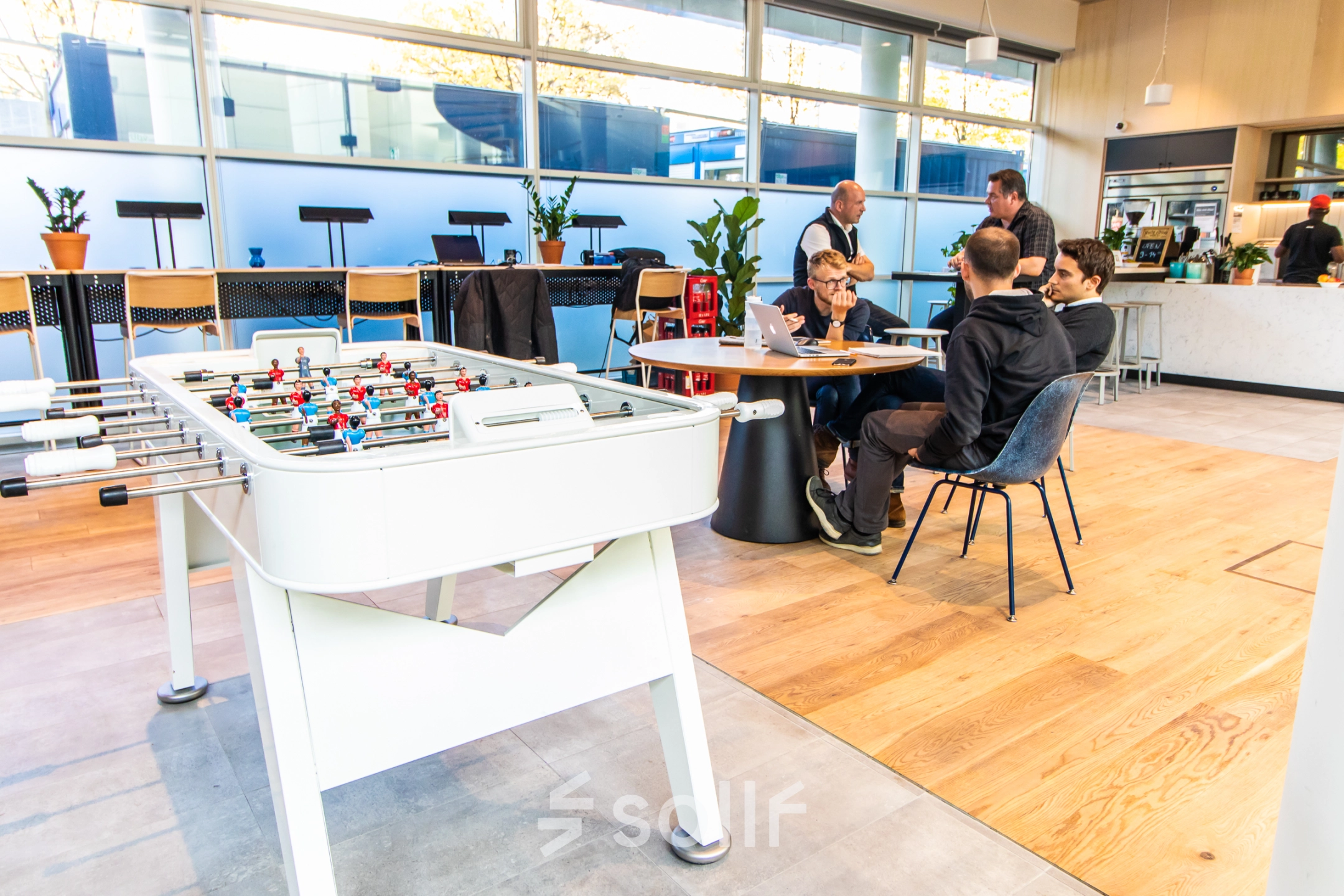 Modern office space at Oskar-von-Miller-Ring 20 in Munich Maxvorstadt, featuring a game table and a group of professionals engaged in a meeting. Ideal for those seeking office space rental.