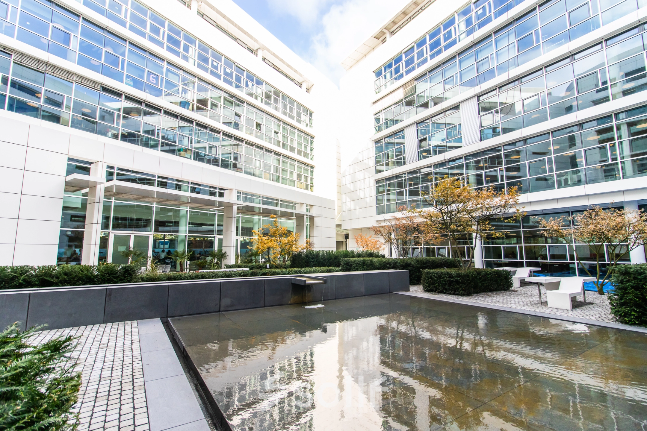 Exterior view of a modern office building at Oskar-von-Miller-Ring 20, Munich Maxvorstadt, featuring a courtyard with seating and water feature.