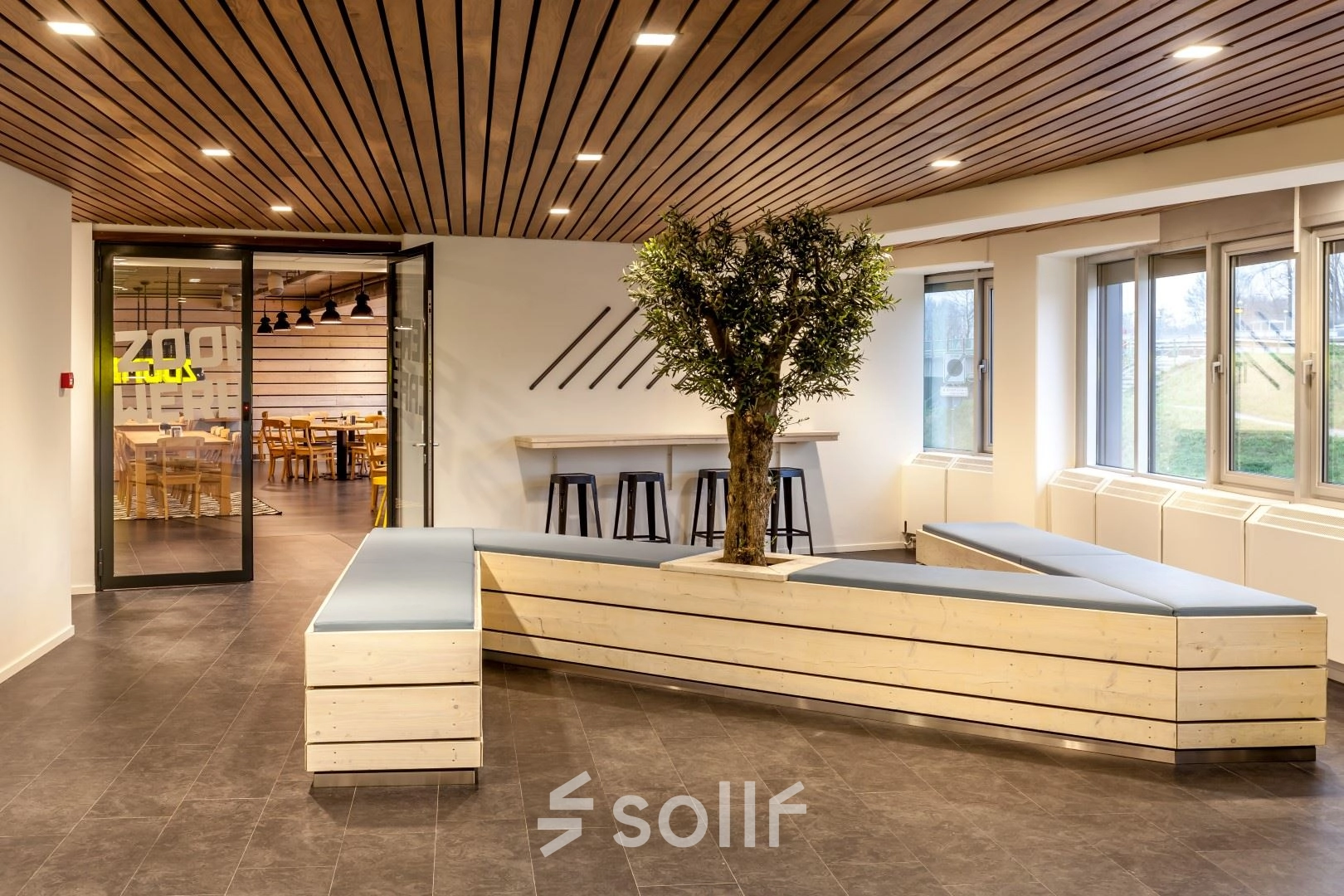 Modern office interior at Zoomstede 19, Nieuwegein featuring a unique wooden seating area with a tree centerpiece, ideal for informal meetings or relaxation. Perfect for businesses seeking distinctive office space rental.