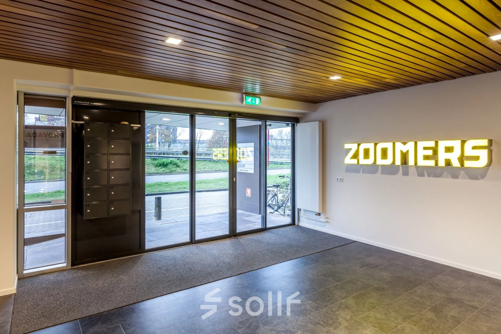 Entrance area at Zoomstede 19 in Nieuwegein, featuring modern glass doors, illuminated signage, and mailbox units, ideal for office space rental.