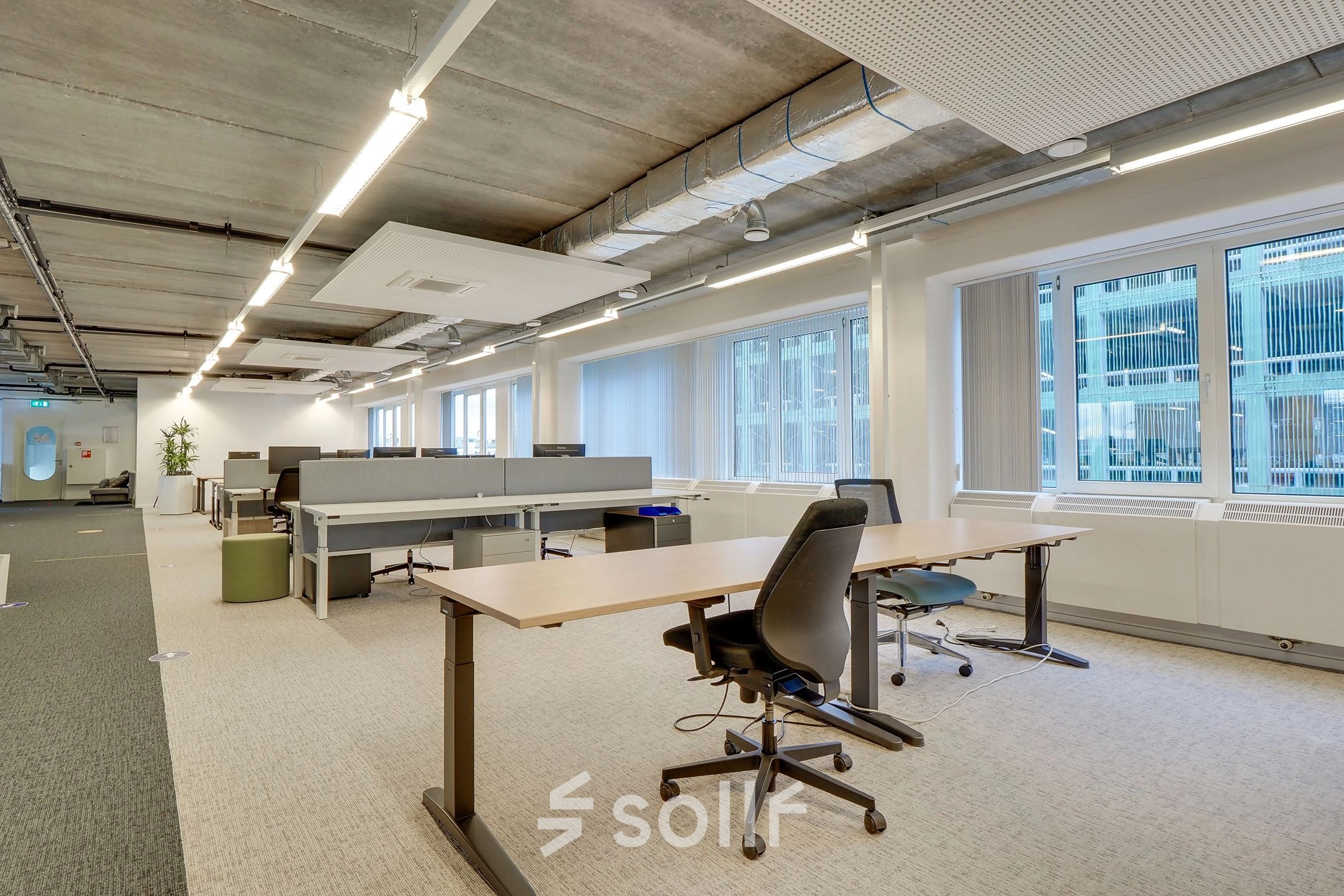 Spacious office interior at Zoomstede 19, Nieuwegein with modern furnishings and large windows. Ideal for those seeking office space rental. Features adjustable desks and ergonomic chairs in an open floor plan.