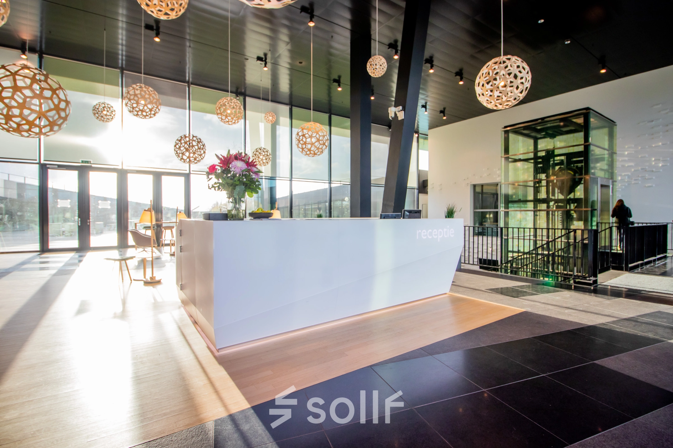 Spacious and modern reception area at Jonkerbosplein 52, Nijmegen, ideal for office space rental. Features unique lighting and a sleek desk, perfect for welcoming visitors.