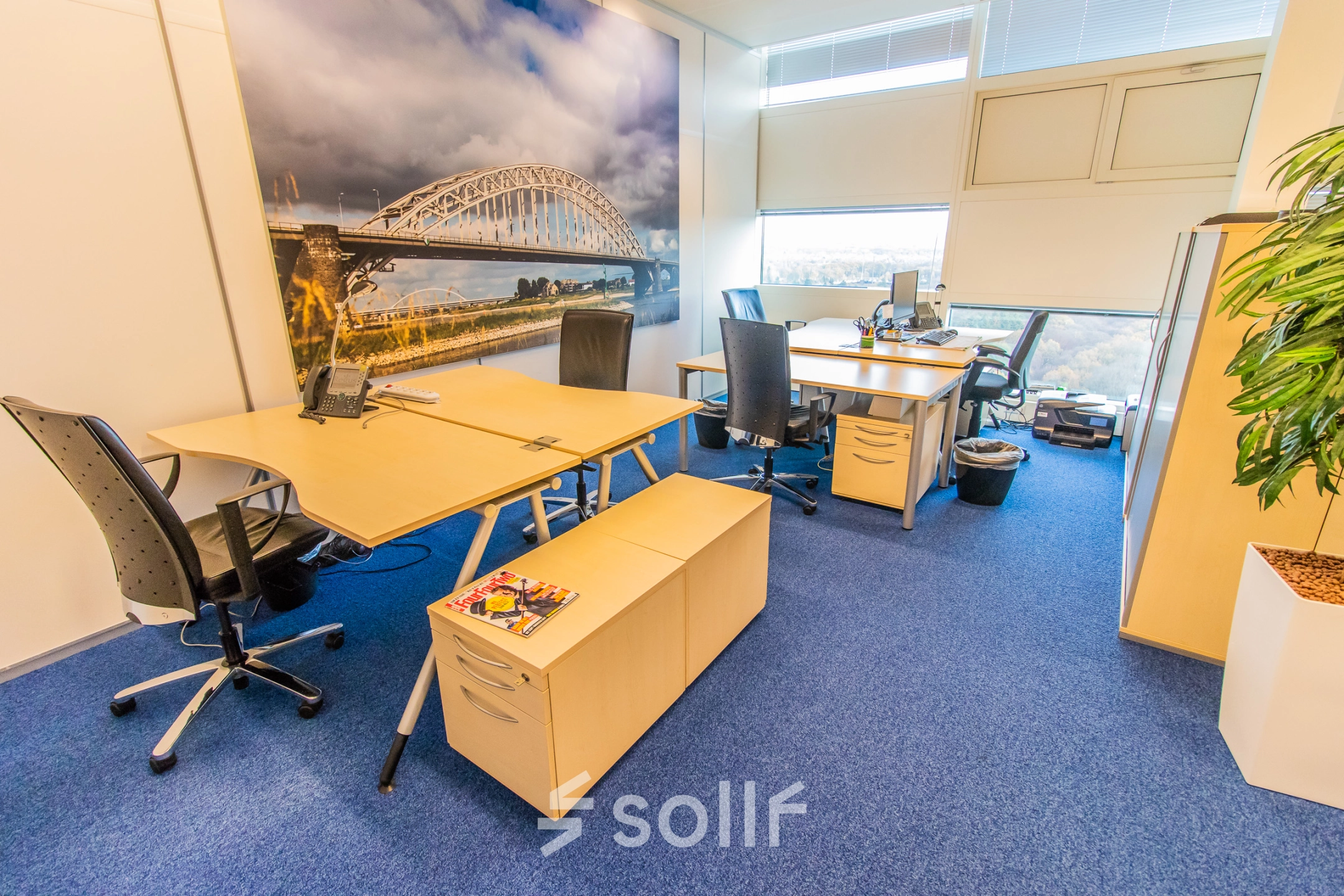 Bright office space at Jonkerbosplein 52 in Nijmegen featuring desks, chairs, and cityscape artwork, ideal for office space rental.