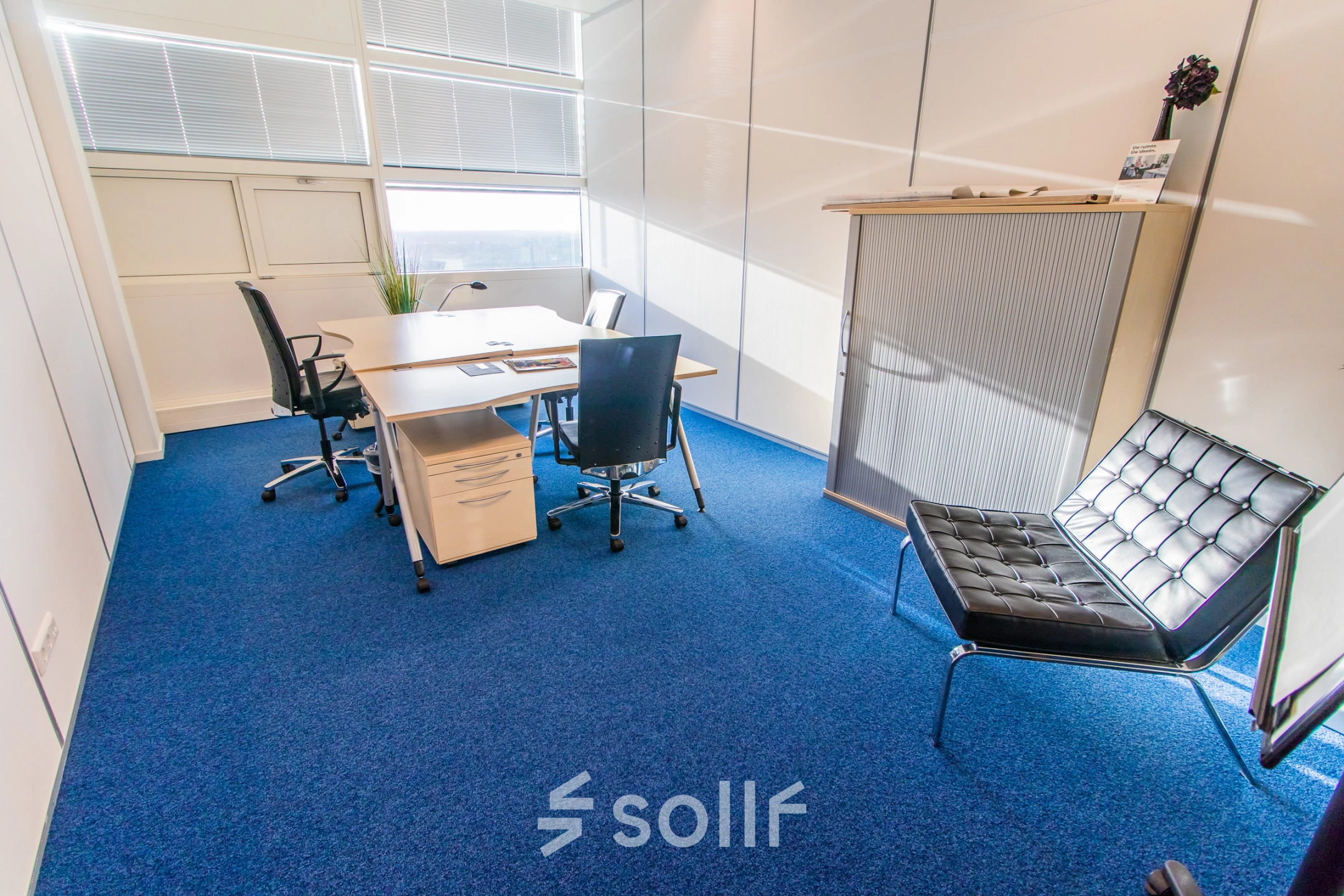 Bright office space in Nijmegen with a central desk and chairs, perfect for businesses seeking office space rental. The well-lit area offers a comfortable setting with modern furnishings.
