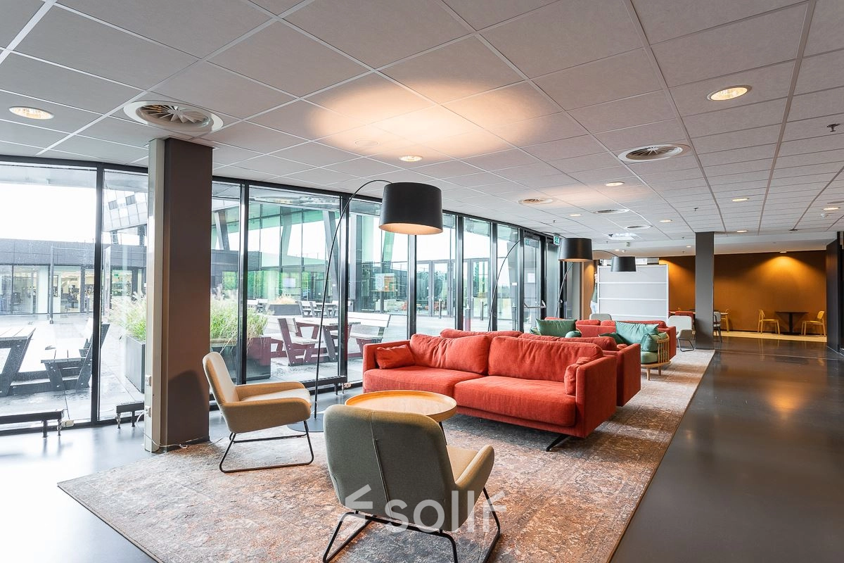 Modern office space for rent at Jonkerbosplein 52 in Nijmegen featuring a stylish lounge area with comfortable seating and large windows.