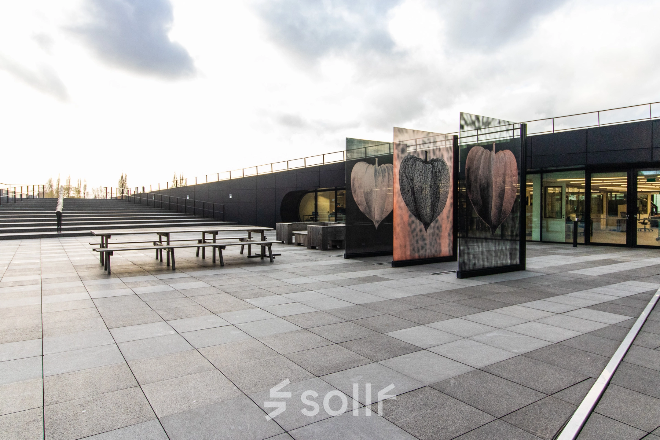 Exterior view of an office space at Jonkerbosplein 52, Nijmegen, showcasing a modern design with ample outdoor seating. Ideal for those looking to rent office space.