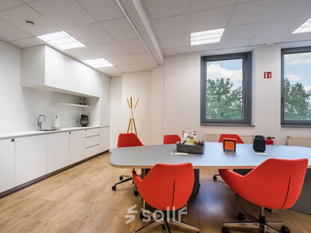 Bright office space at Südwestpark 67, Nürnberg Röthenbach featuring modern furnishings and red chairs around a meeting table, ideal for office space rental.