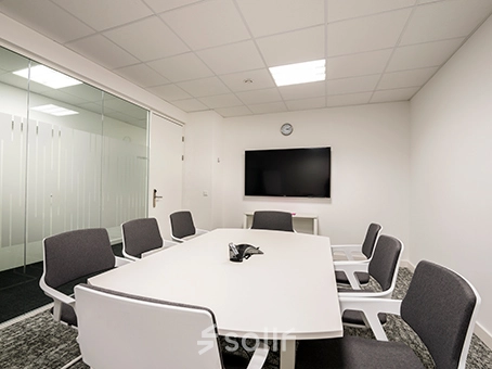 A furnished meeting room in an office to rent at Südwestpark 67, Nürnberg Röthenbach, featuring a long table, chairs, and a TV on the wall.
