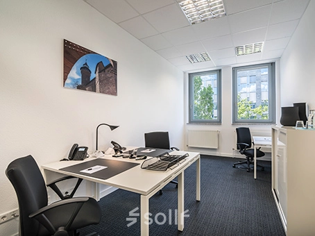 Bright office space with two desks, chairs, and a view of the outside greenery at Südwestpark 67, Nürnberg Röthenbach, perfect for office space rental.