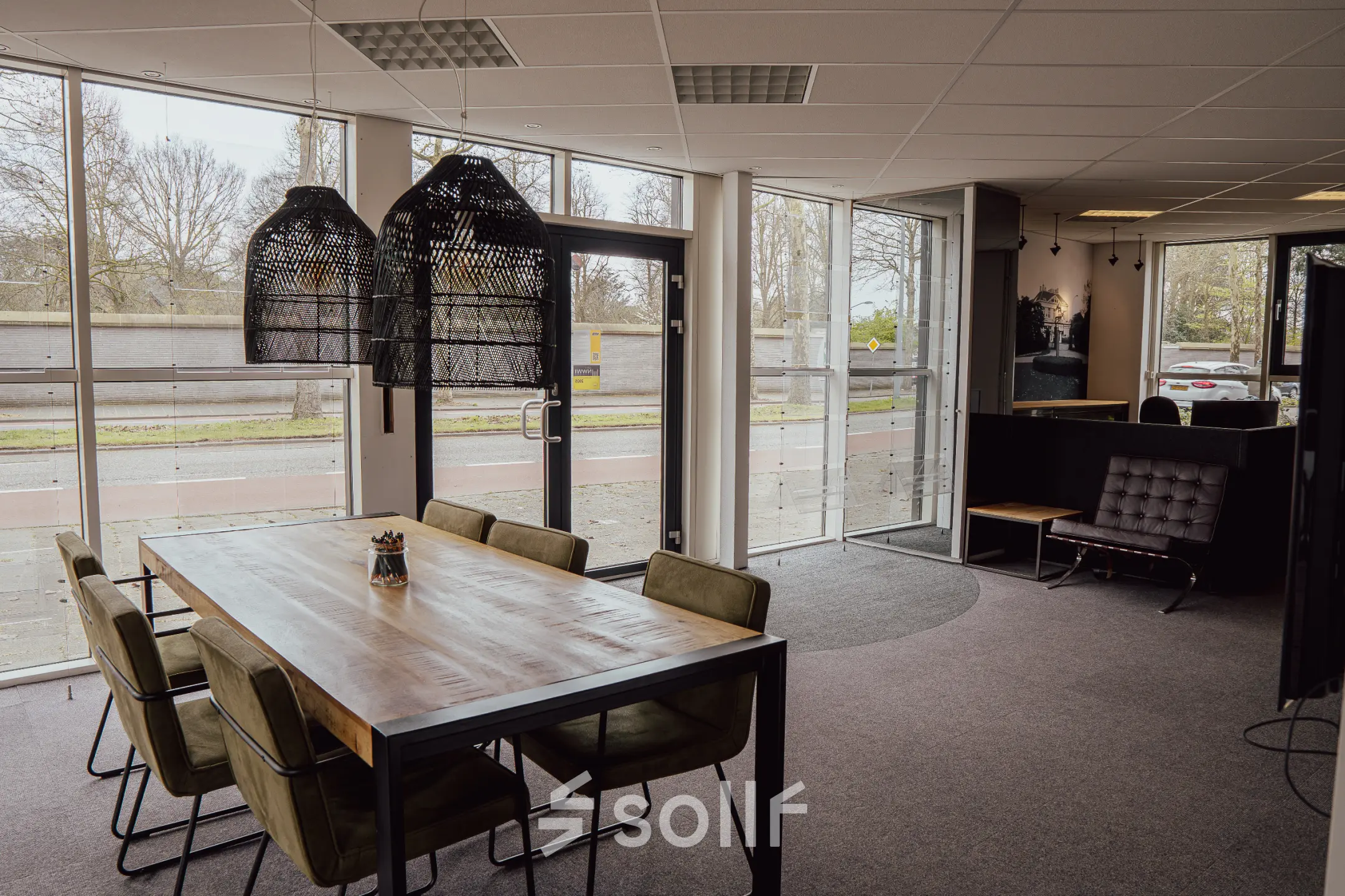 Bright office space with large windows and a wooden table with chairs at Abdis van Thornstraat 74, ideal for office space rental in Oosterhout Nb.