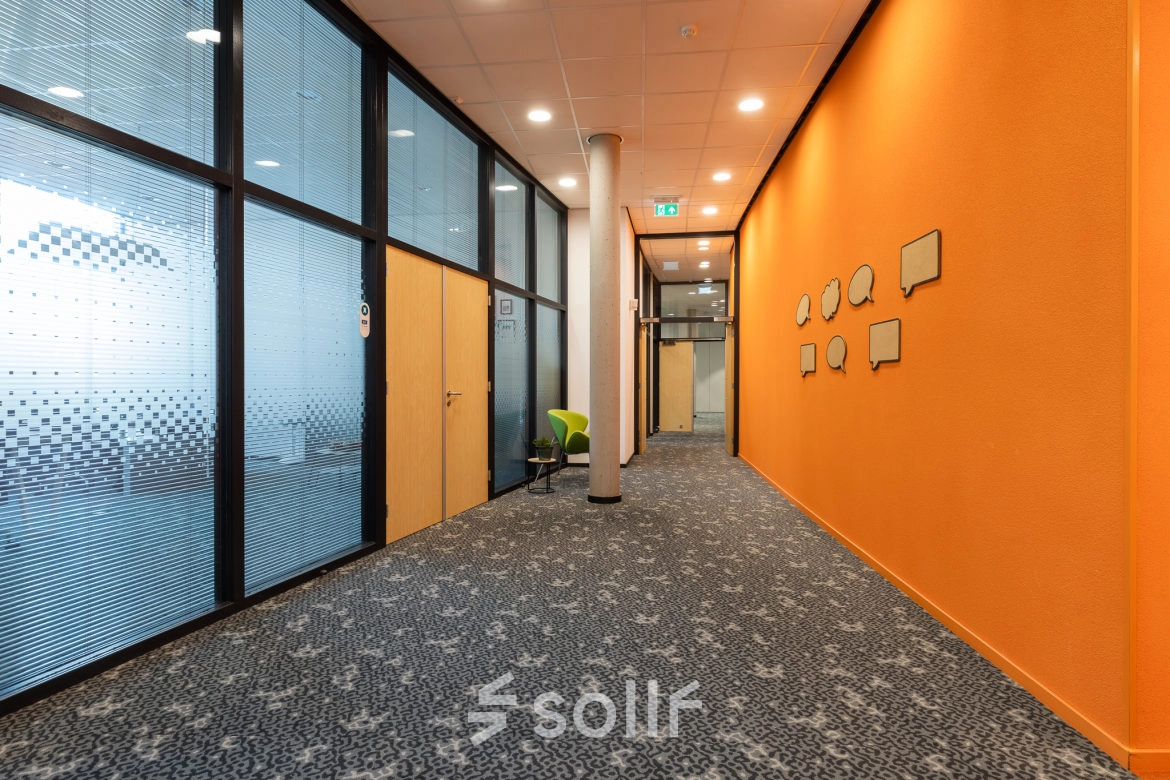 Bright office corridor at Veengang 1, Oosterwolde, ideal for office space rental, featuring vibrant walls and carpeted floors.