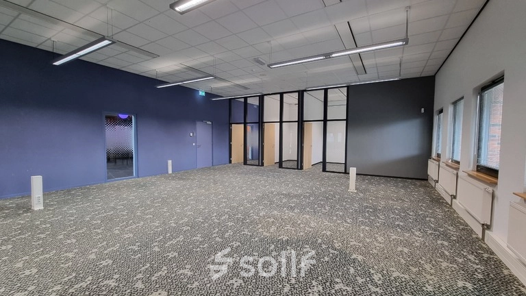 Spacious office to rent at Veengang 1, Oosterwolde, featuring patterned carpet, large windows, and ample natural light.