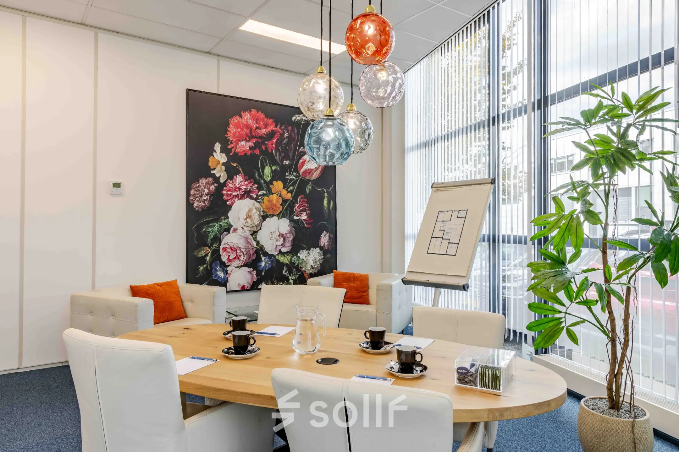 Bright and inviting conference room at Leeghwaterstraat 25 in Reeuwijk with a round table, modern pendant lights, and floral wall art. Ideal for office space rental.