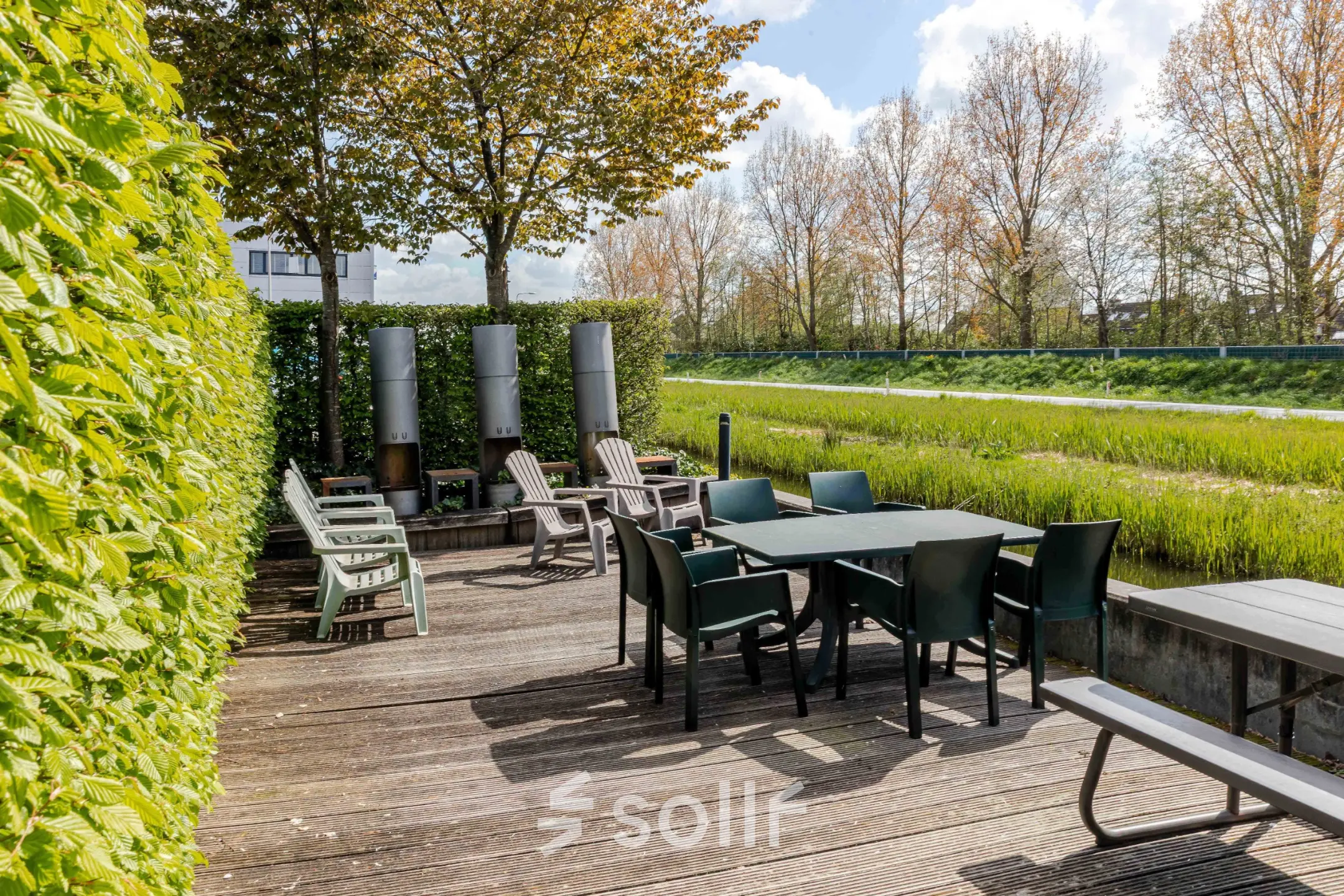 Outdoor patio area with tables and chairs surrounded by greenery, available for rent office space at Leeghwaterstraat 25, Reeuwijk.