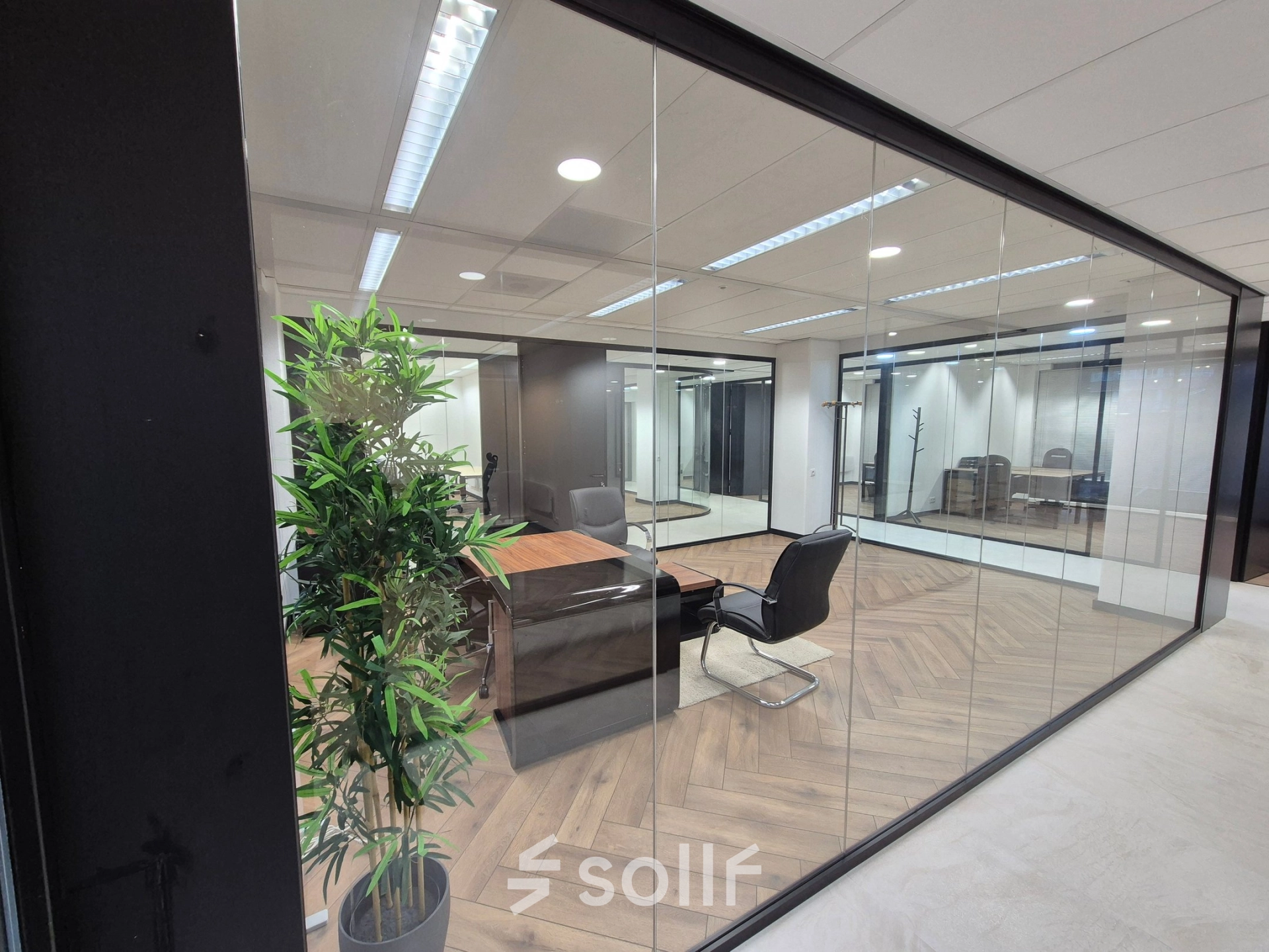 Glass-walled office at JC van Markenlaan 3 in Rijswijk showcasing a stylish meeting area with wooden flooring and contemporary furniture, perfect for office space rental.