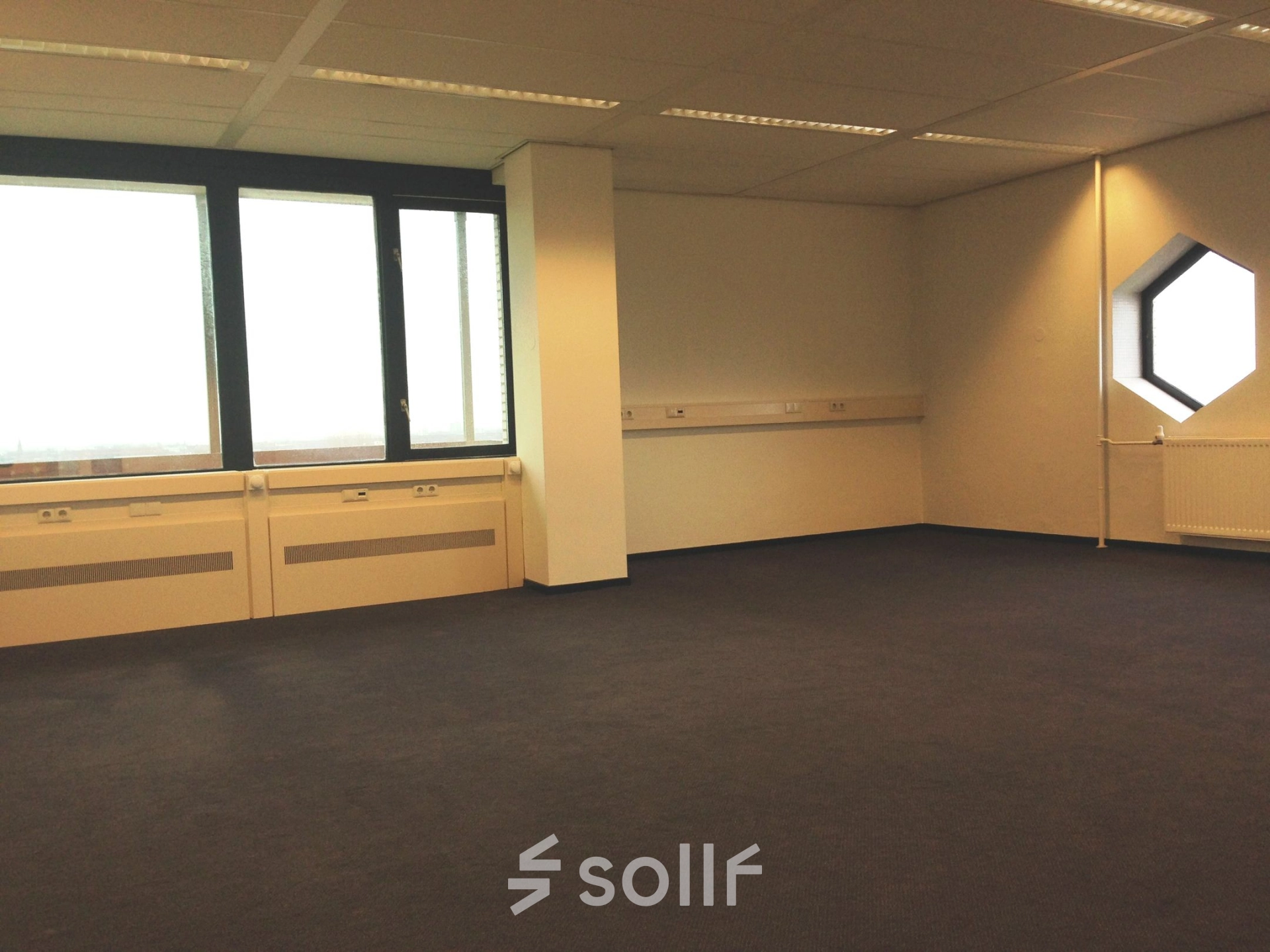 Spacious office available for rent at JC van Markenlaan 3, Rijswijk, featuring large windows and carpeting. Ideal for office space rental.