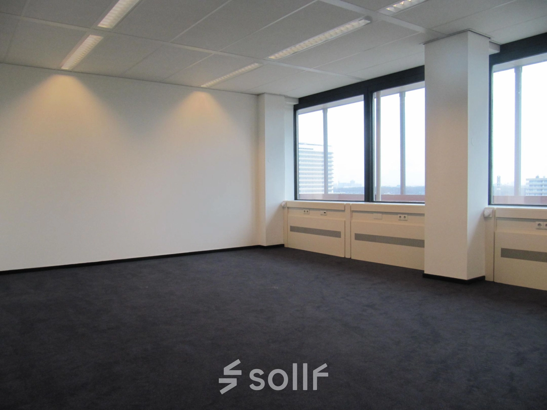 Spacious empty room with large windows overlooking the city at JC van Markenlaan 3, ideal for office space rental.