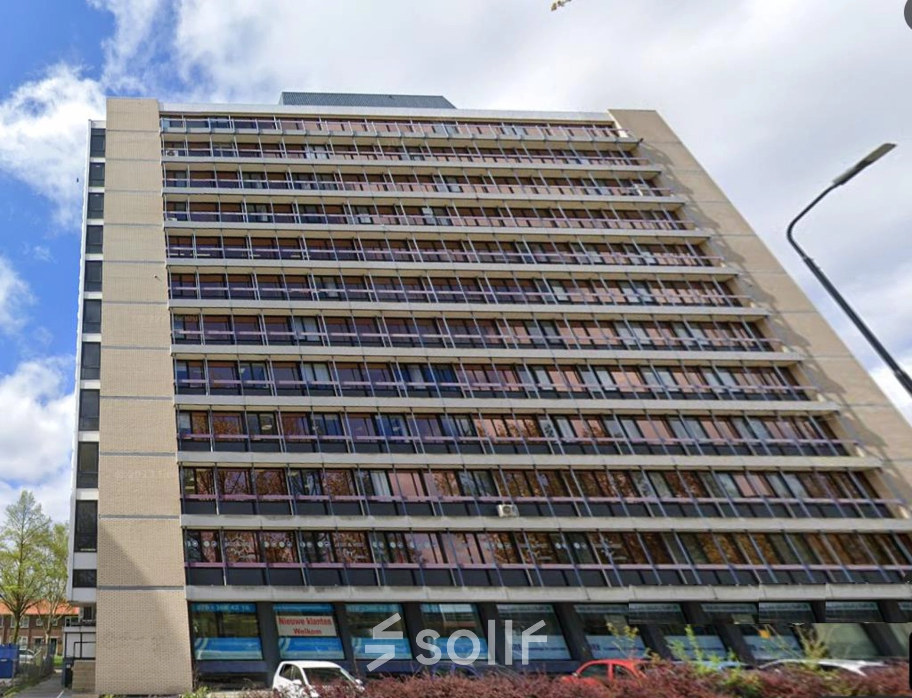 Exterior view of a multi-story office building at JC van Markenlaan 3, Rijswijk. The building has large windows and is suitable for office space rental. Several parked cars are visible in front.