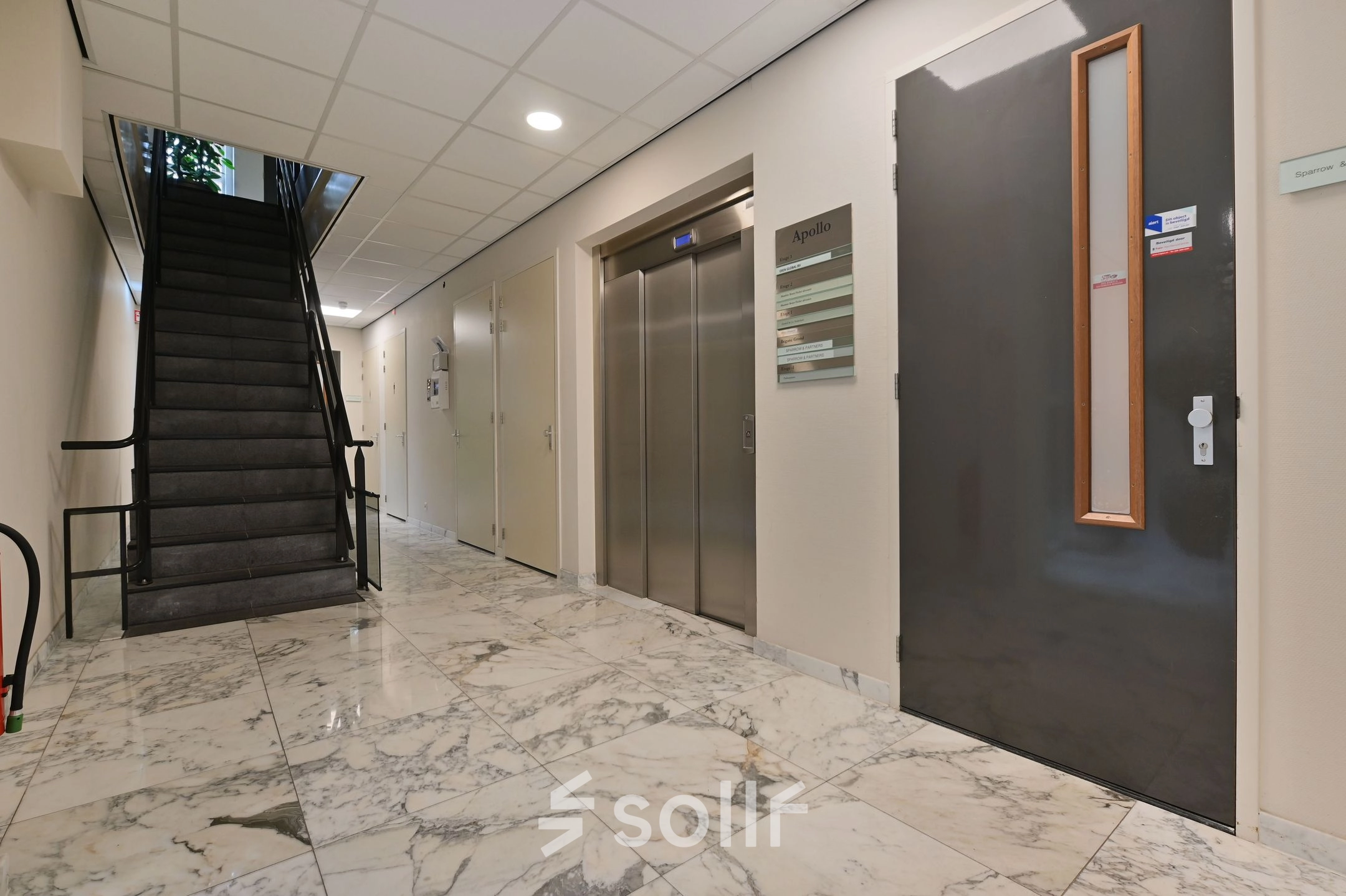 Interior view of an unfurnished office entrance at Laan van Vredenoord 17-19, featuring marble flooring, an elevator, and a staircase, ideal for office space rental.