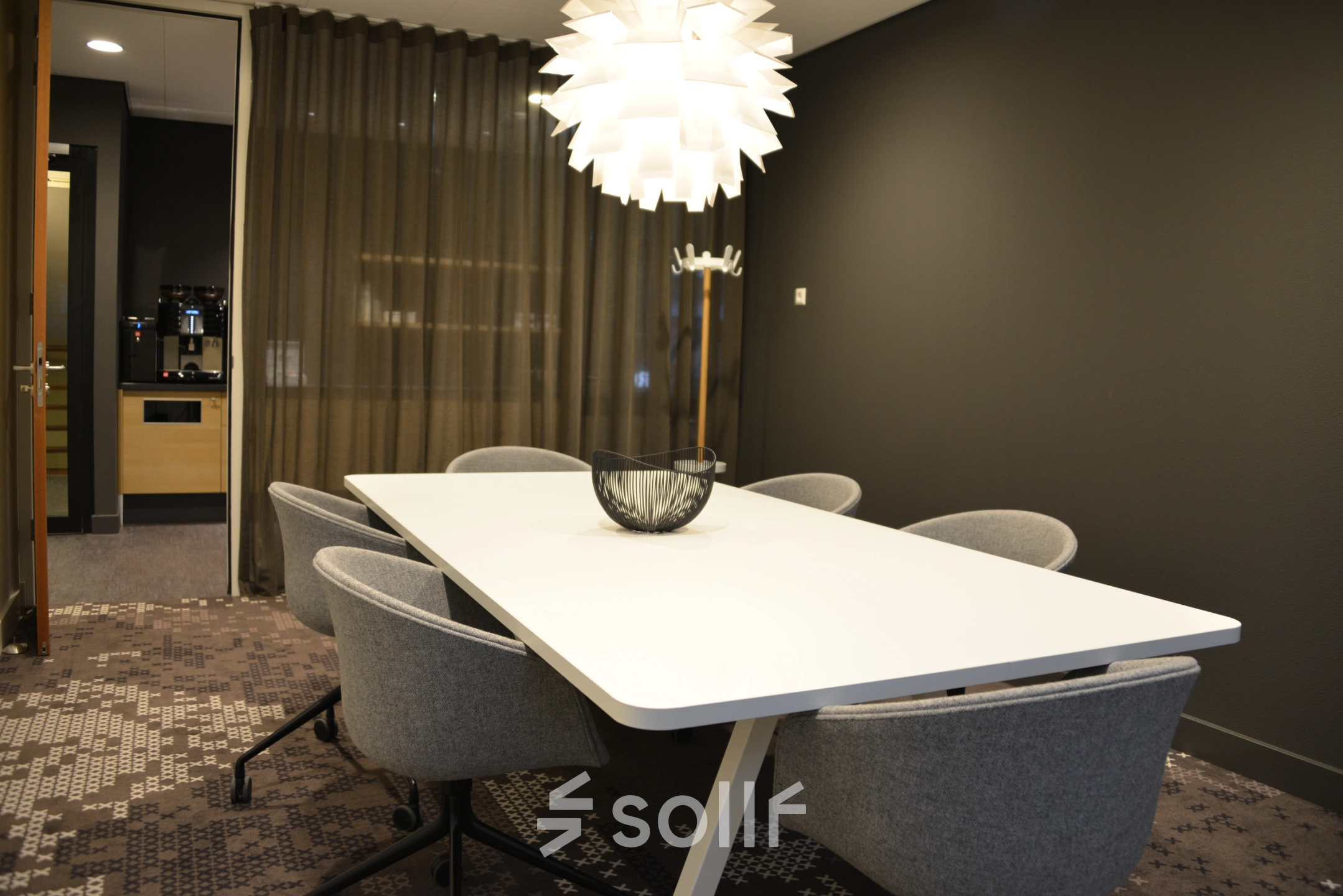 Modern office space to rent at Laan van Vredenoord 33, Rijswijk, featuring a sleek meeting table and chairs under stylish lighting.