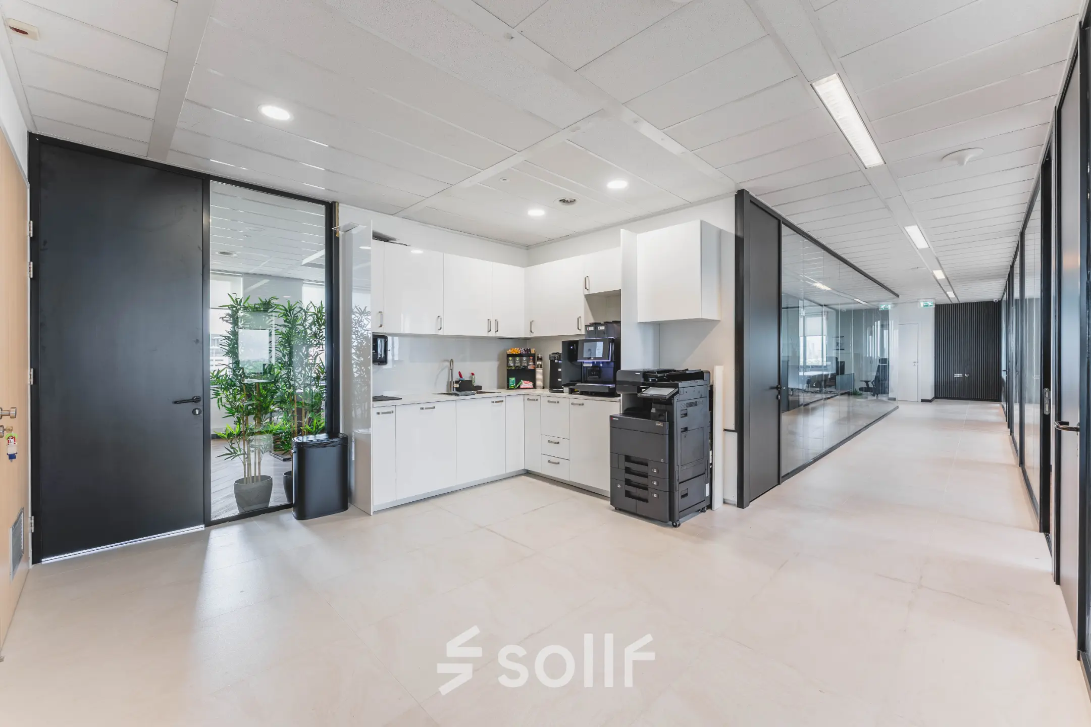 Modern office space at Laan van Zuid Hoorn 70, Rijswijk featuring a sleek corridor with a kitchen area and glass-partitioned offices ideal for office space rental.