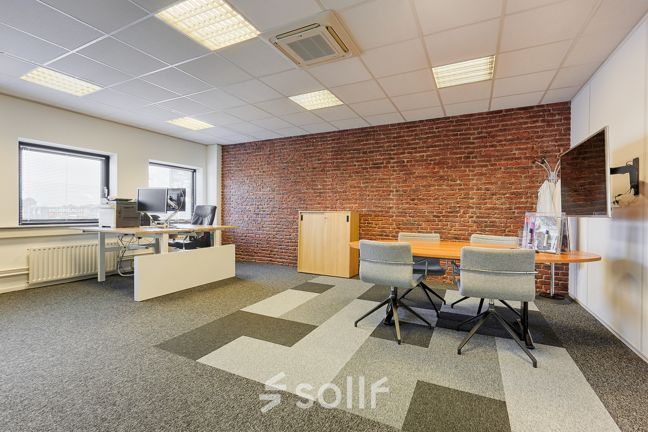 Modern office space at Patrijsweg 62, Rijswijk, featuring contemporary furnishings, a brick accent wall, and ample lighting, ideal for office space rental.