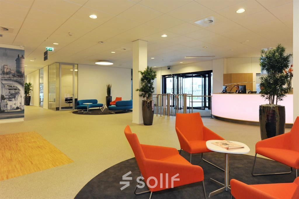 Spacious office reception area at Patrijsweg 62, Rijswijk, featuring modern decor with orange and blue seating and a sleek reception desk. Ideal for those seeking office space rental.