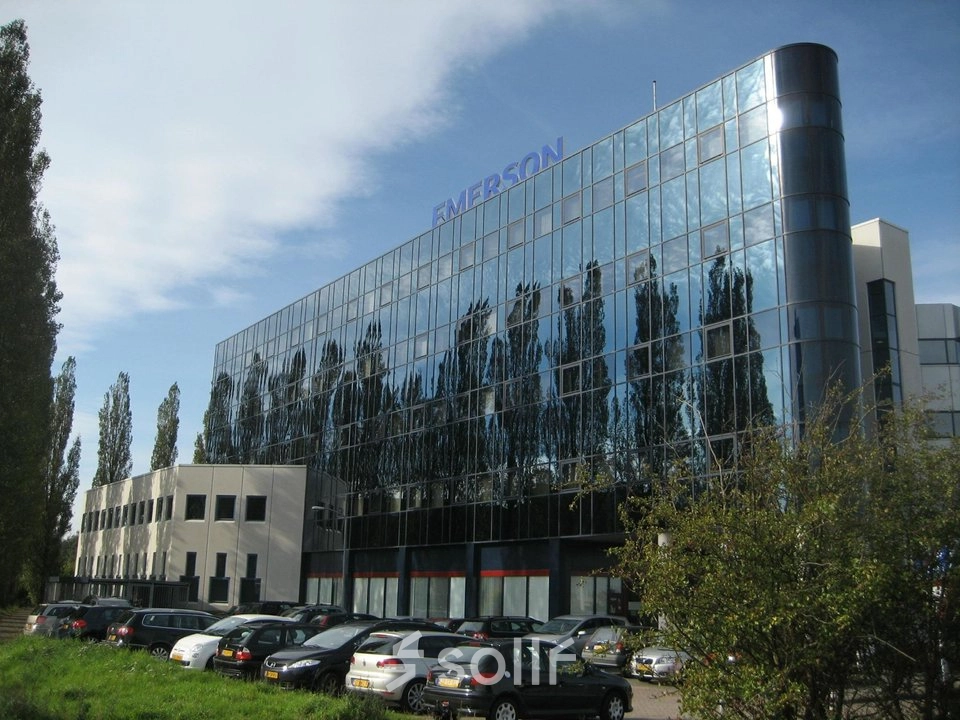 Modern office building with reflective glass facade at Patrijsweg 62, Rijswijk, surrounded by trees and a parking area. Ideal for office space rental.