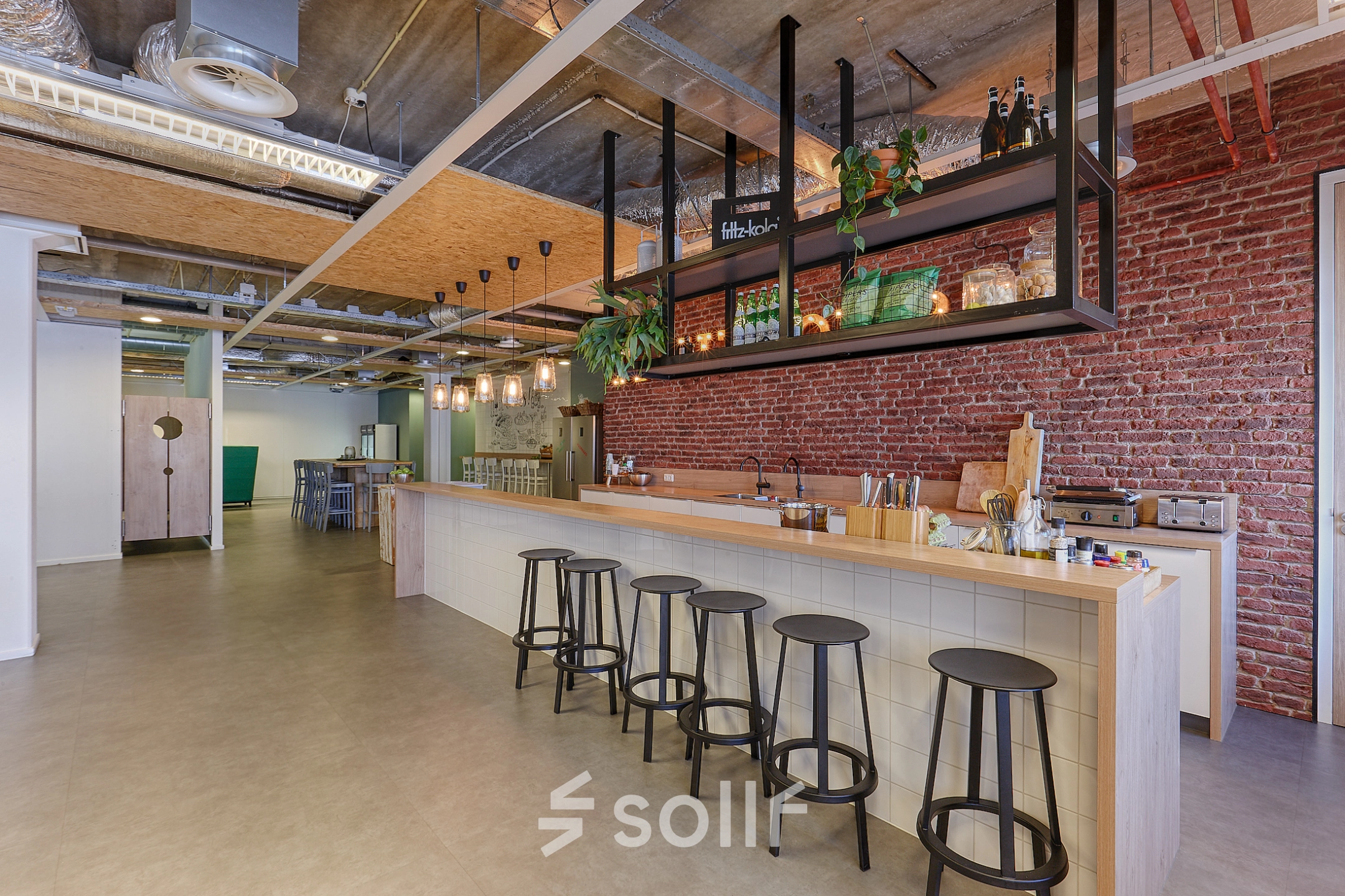 Furnished office space at Patrijsweg 62, Rijswijk, featuring a modern lounge area with a long counter and bar stools, exposed ceilings, and decorative lighting.