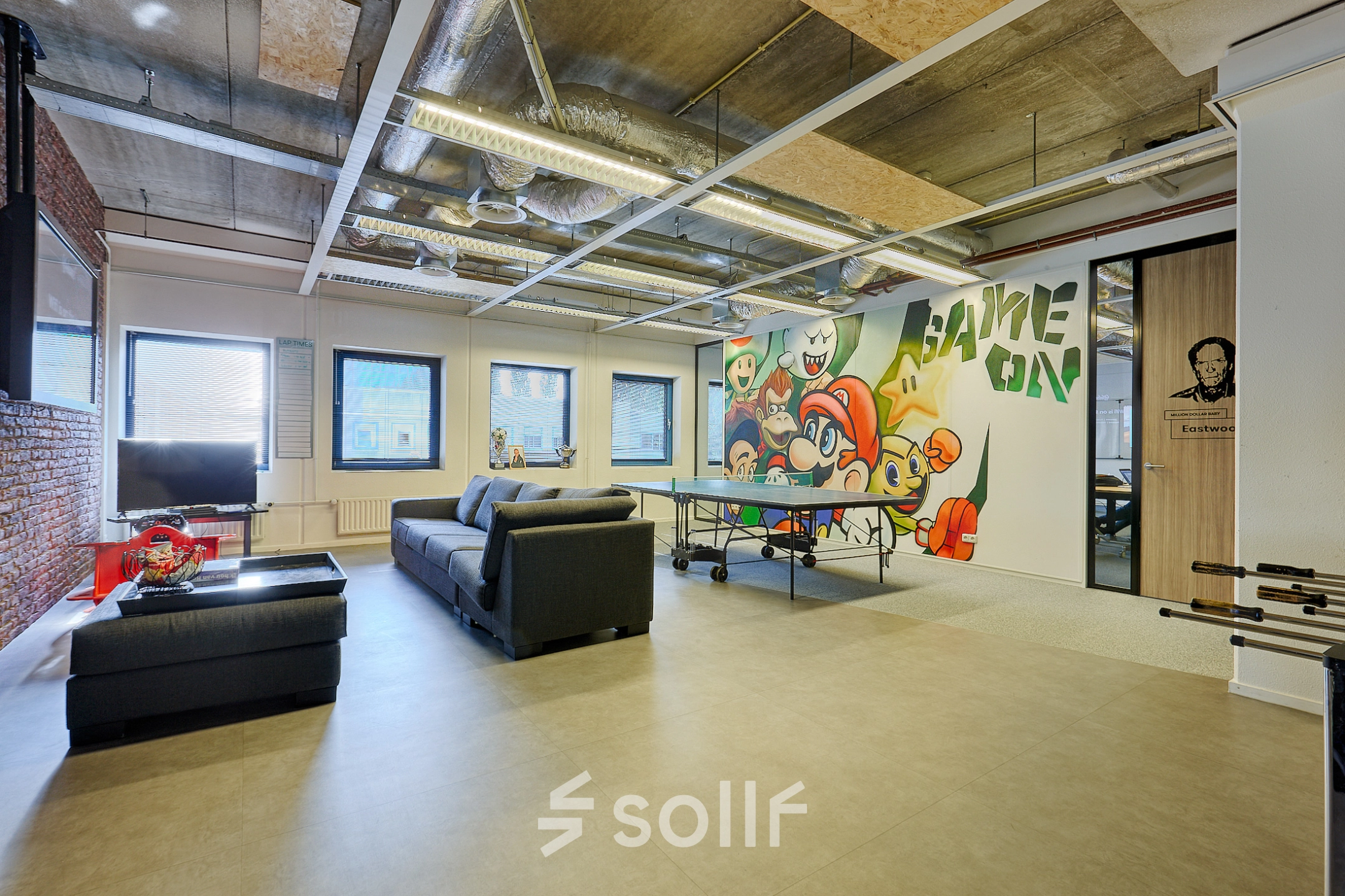 Spacious office to rent with modern furnishings, featuring a playful mural and a ping pong table, situated at Patrijsweg 62, Rijswijk. Ideal office space rental for creative work.