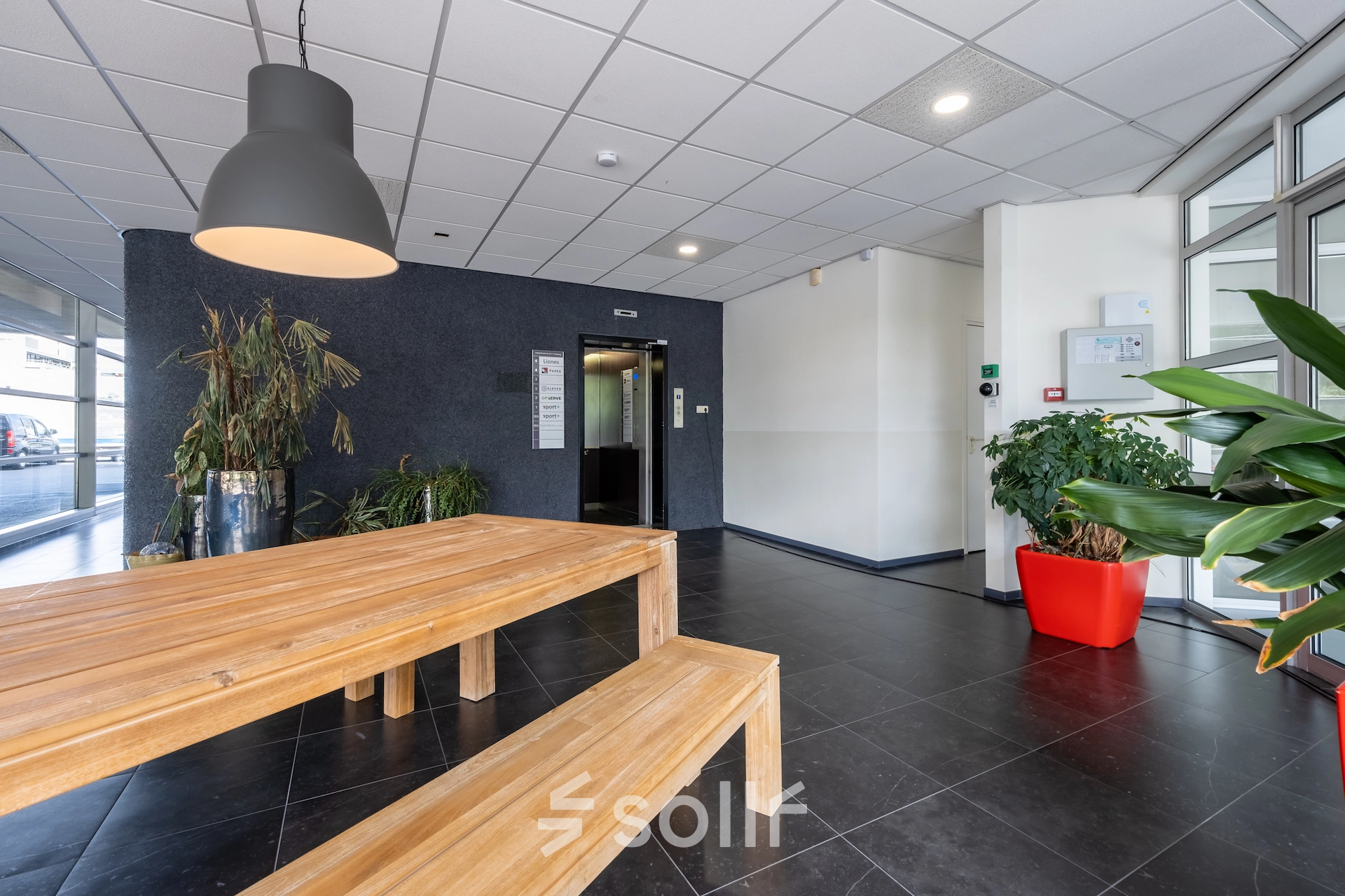 Furnished office interior at Polakweg 7, Rijswijk featuring wooden benches and lush greenery, ideal for those seeking office space rental.