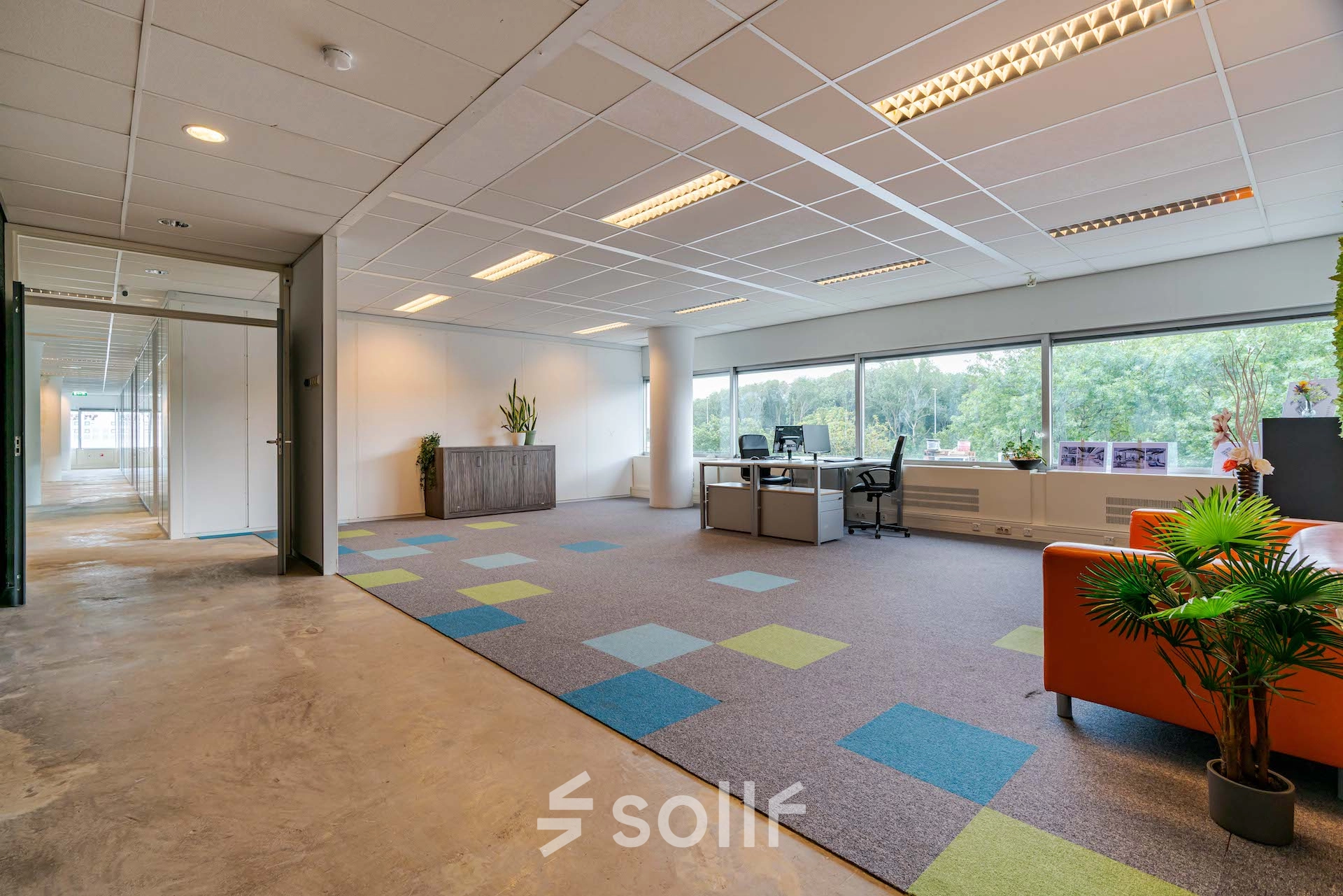 Bright office space at Polakweg 7, Rijswijk, featuring modern furnishings, colorful carpet, and large windows. Ideal choice for office space rental.